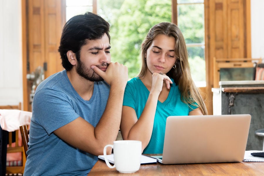 Young couple looks confused by AFUE while working on a laptop together. terms.
