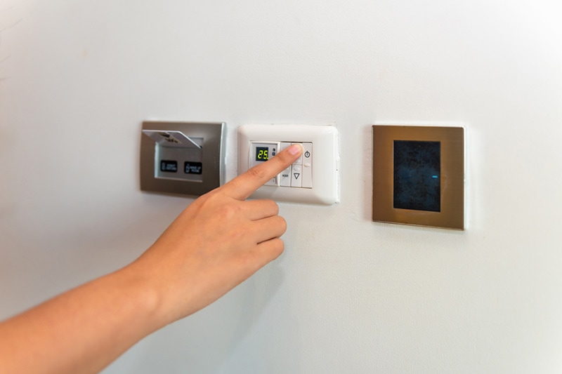 A hand changing the temperature of a thermostat | Heat Pump vs. Furnace | Which Is Right For You? | Lakeview, LA