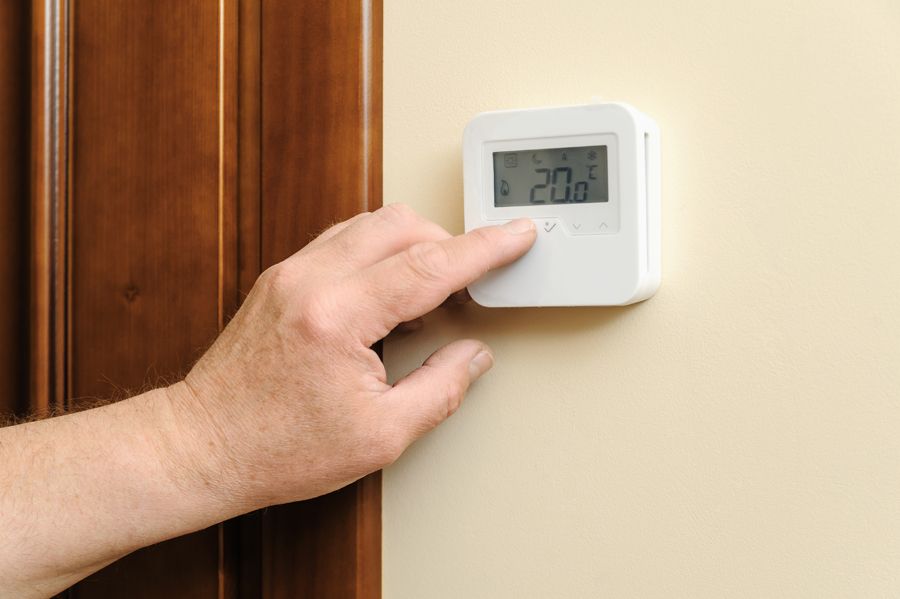 A person fiddling with their thermostat.